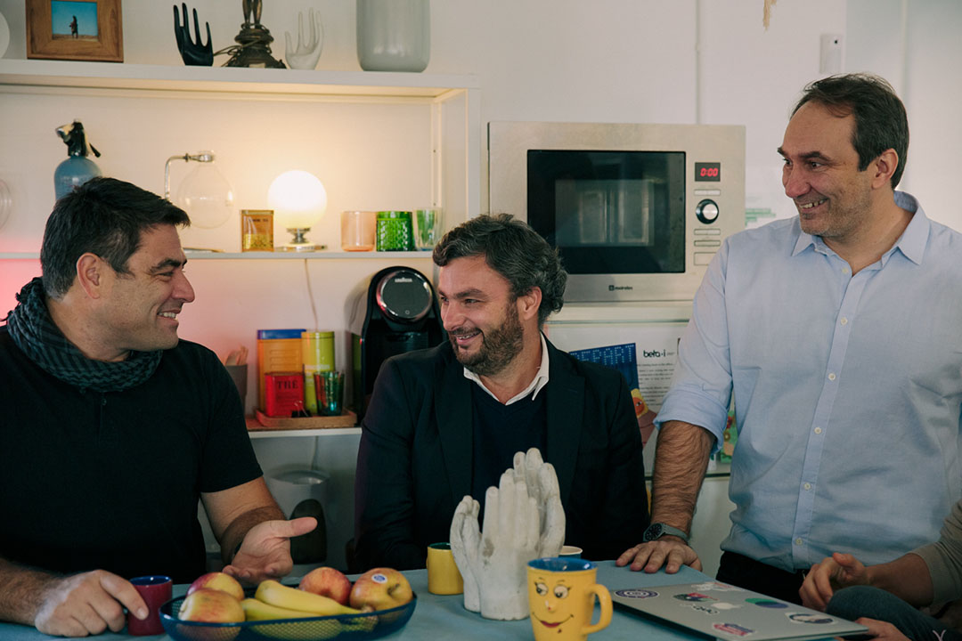 3 men talking with each other and smiling